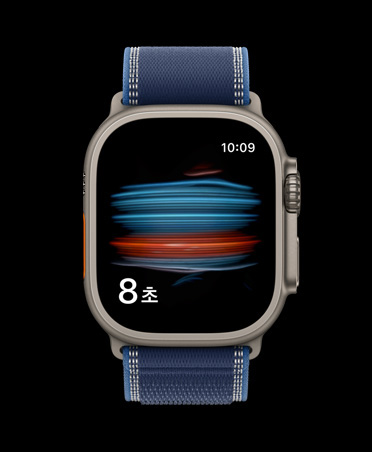 건강 앱의 혈중 산소 포화도 검사 화면이 표시된 내추럴 색상 티타늄 케이스의 Apple Watch Ultra 3, 그리고 블루/브라이트 블루 색상 트레일 루프