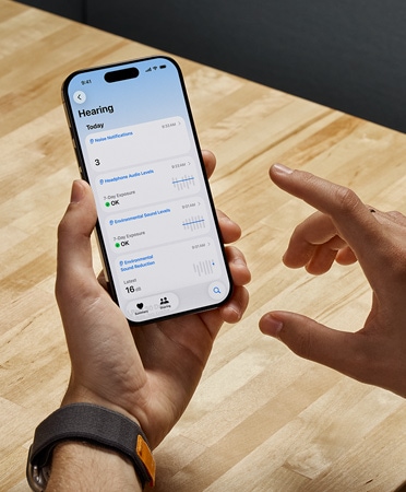 Osoba używająca AirPods Pro 2 trzyma iPhone’a, korzystając z nowej funkcji Badanie słuchu