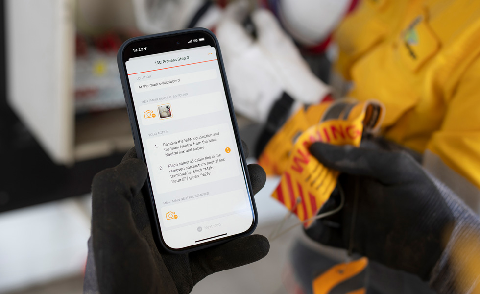 Hænder holder en iPhone, der viser instruktioner til at udføre en tavletest, med teksten “13C Process Step 3” på skærmen